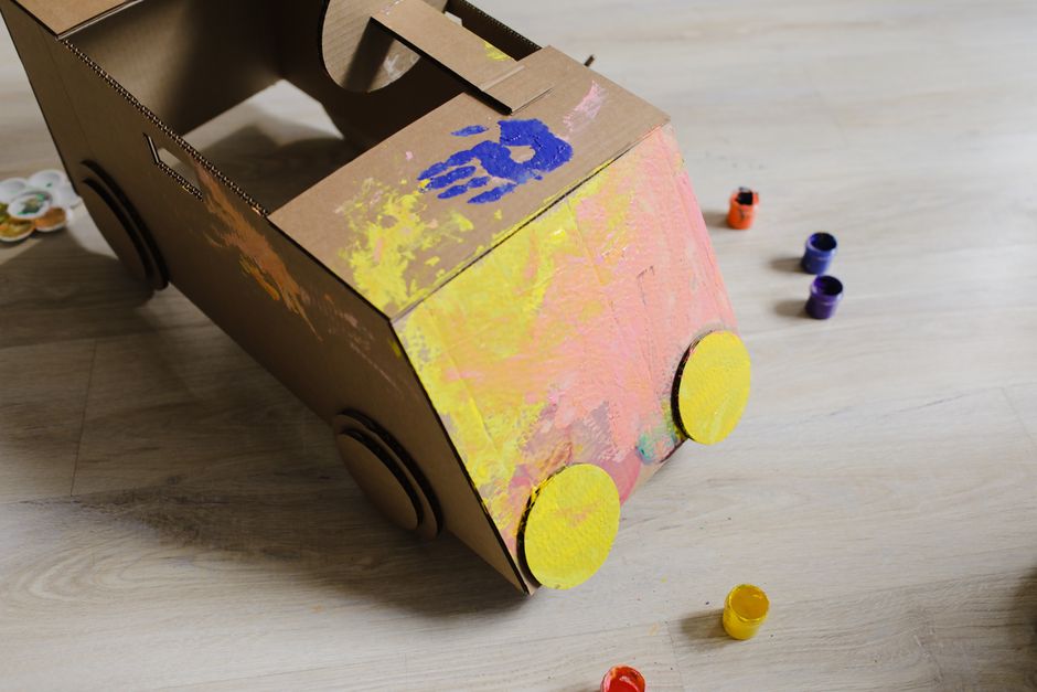A child's painted cardboard car, built from a box and craft supplies